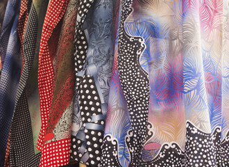 Rows of colorful silk scarves hang on a market stall