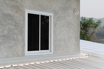 Aluminum sliding window on gray concrete wall.