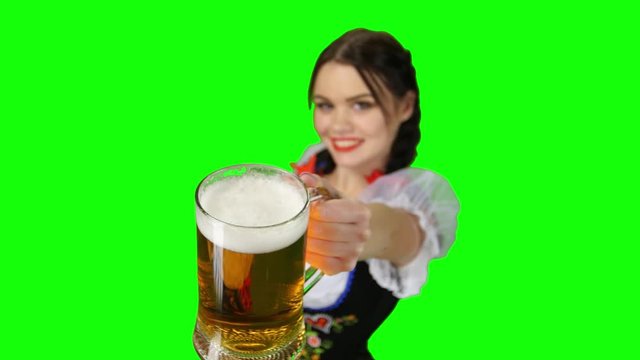 Girl in Bavarian costume offers a glass of beer. Green screen