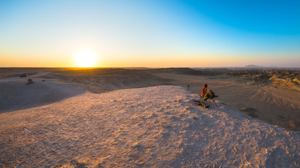Rear view of woman sitting on rocks and looking at expansive view over the scenic Namib desert at...