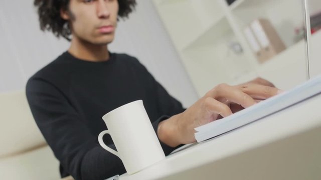 The young Afro-American sits in a chair and works with the computer