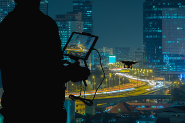 Silhouette of Man using drone to monitor the city  night traffic.