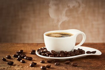 Coffee cup and saucer on a wooden table with coffee beans