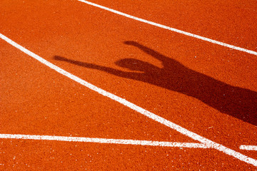 The shadow of man on red running track