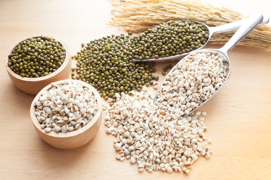 Job's tears and Green beans in scoop, in cup and ear of paddy on wood table
