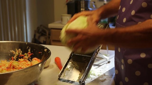 Man shredding row organic cabbage for salad
on mandolin vegetable slicer
