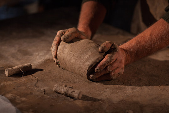 Hands of the potter knead clay.