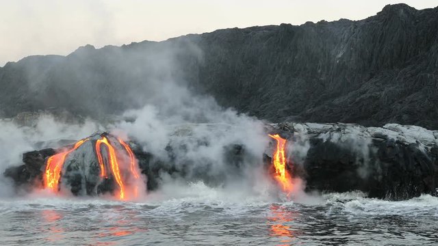 Lava flowing into the ocean from lava volcanic eruption on Big Island Hawaii, USA. Lava stream flowing in Pacific Ocean from Kilauea volcano around USA. Seen from water, Steadicam, 59.94 FPS, 2016.