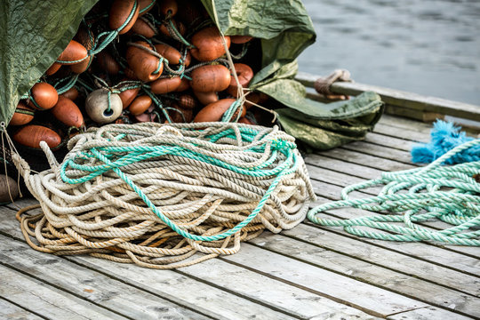 Many fishing nets and floats, stacked on a wooden dock. Fisheries, fishing. Fishing industry.  Background.
