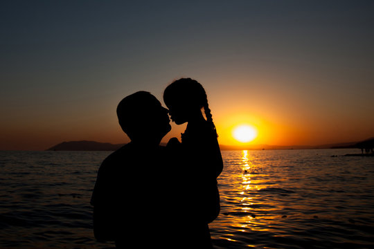 Father and daughter playing on the beach at the sunset time. Con