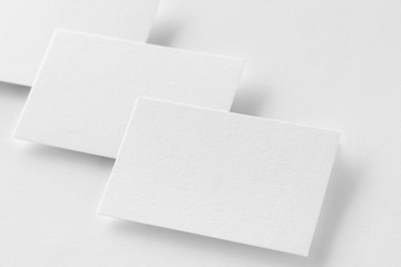 Three business cards mockup at textured white paper background.