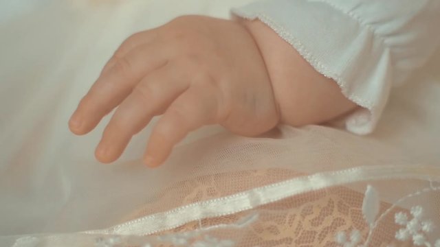 Little baby hand in white dress, close up 