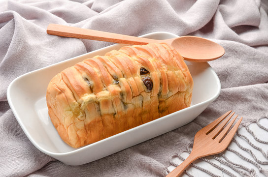 Breakfast with fresh raisin bread ,spoon and fork on white plate