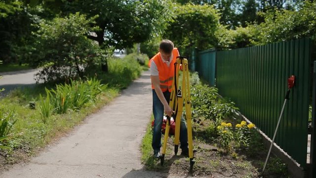 Worker in orange vest fold geodetic device for surveying