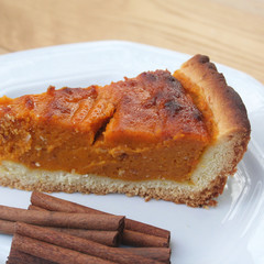 Fetta di torta alla zucca con cannella su piatto su tavolo di legno. Dolce per il giorno del Ringraziamento.