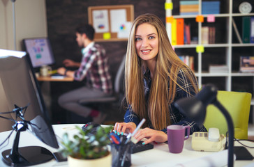 Two young people working on their computers, focus on the woman
