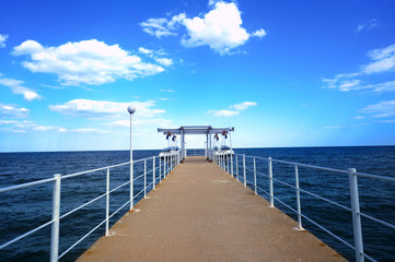 Obraz premium Molo ciągnące się do morza z pięknym błękitnym niebem i chmurami latem w kurorcie Złote Piaski w Bułgarii. Przebij pustą drogę w pięknym morzu i niebie.