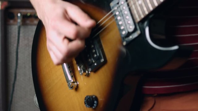 Guitarist plug cable in electric guitar, turn volume up and strumming with plectrum
