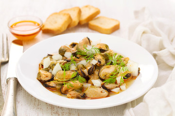 salad mussels with onion in sauce in white plate on wooden backg