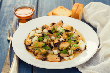 salad mussels with onion in sauce in white plate on wooden backg