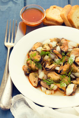 salad mussels with onion in sauce in white plate on wooden backg