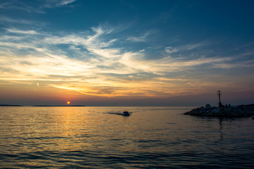 Fototapeta na wymiar Boot kehr in den Hafen zurück bei Sonnenuntergang in Kroatien