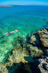 Fototapeta premium Schöne Frau im Bikini Schnorchelt durch Türkises Wasser an der Küste