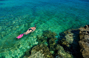 Naklejka na ściany i meble Schöne Frau im Bikini Schnorchelt durch Türkises Wasser an der Küste