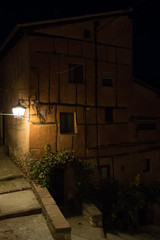 Fototapeta na wymiar Casa junto a una escalera de noche en un pueblo antiguo español con un farol encendido