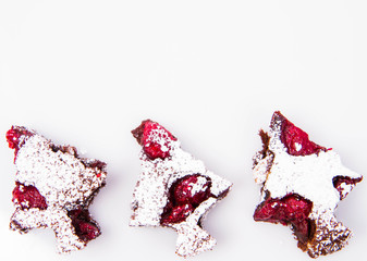 Christmas tree shaped raspberry brownies covered with powdered sugar on a white background