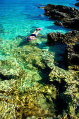 Fototapeta na wymiar Schöne Frau im Bikini Schnorchelt durch Türkises Wasser an der Küste
