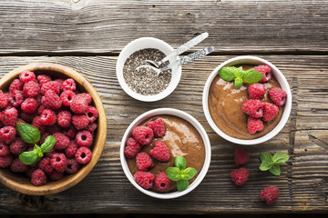 Chocolate Banana Smoothies served fresh juicy ripe raspberries with a sprig of mint in portioned bowls on  wooden background. The horizontal design