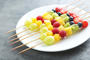 Fresh fruit on skewers on a grey wooden table
