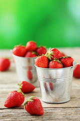 Fresh and tasty strawberries in bucket on a grey wooden table