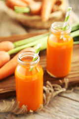 Fresh carrot juice in bottles on a grey wooden table
