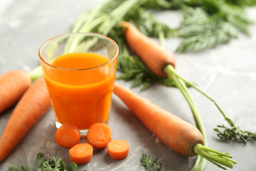 Fresh carrot juice in bottles on a grey background