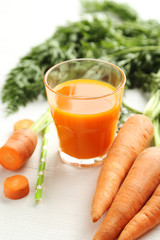 Fresh carrot juice in glass on a white wooden table