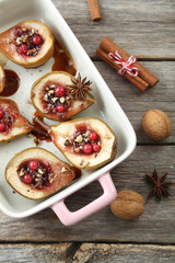 Baked pears with honey, walnuts and cranberries on grey wooden t