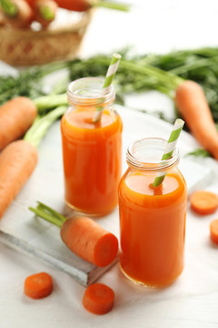 Fresh carrot juice in bottles on a white wooden table