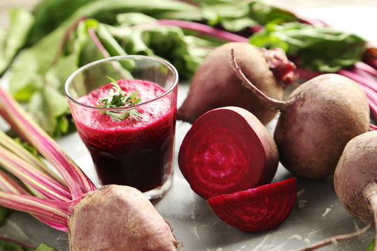 Fresh beets juice in glass on a grey background