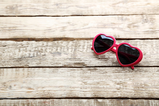 Pink sunglasses on grey wooden table