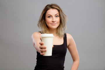 Young woman giving hot coffee to camera