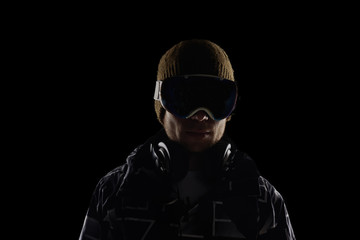 Snowboarder in mask on black background. Dark concept with backlight. Extreme sport live.