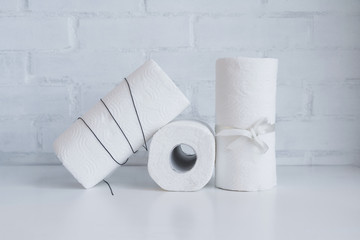 White paper towel rolls on white board against white brick wall