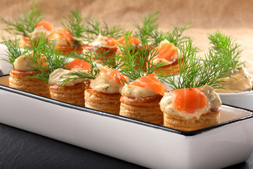 Salmon appetizer with dill dip in puff pastry on stone tray