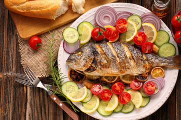 Grilled fish with baguette and vegetables on the plate