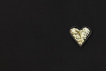 Small golden heart  made of little stars on black background. Christmas concept