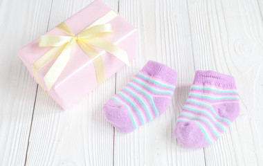 baby socks and gift box on wooden background