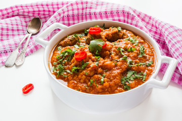 Spicy lentil and meatball soup with parsley. Casserole on white table.