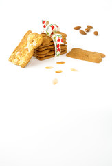 Stack of Spekulatius with Almonds ( Spiced Biscuits with Almonds ) decorated with Christmas Bow, surrounded by almonds and more biscuits on white background. 
